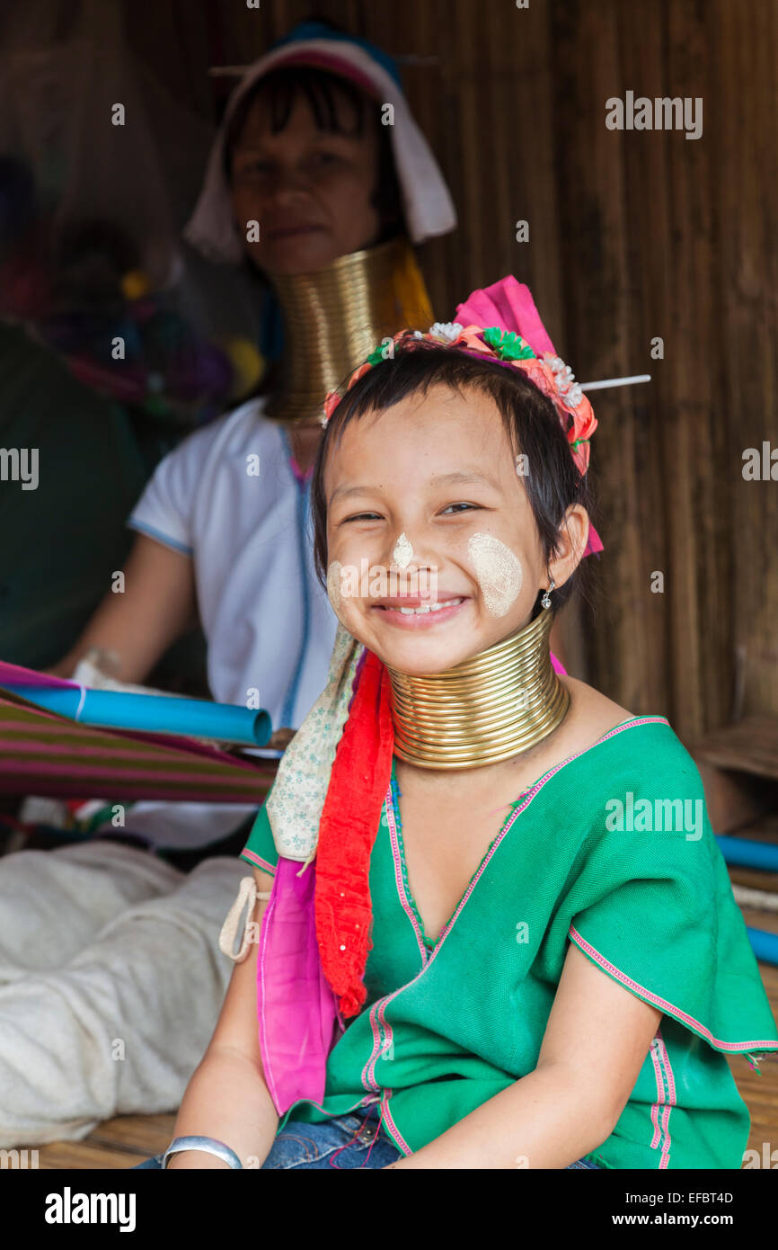 Cute young Burmese long neck girl with a green blouse and sun screen in Karen Padong village, Chiang Rai, Thailand, smiling Stock Photo