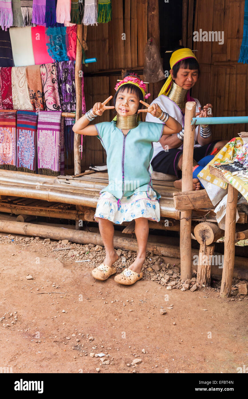 Cute young Burmese long neck girl and sun screen in Karen Padong village in her mother's souvenir shop, Chiang Rai, Thailand Stock Photo