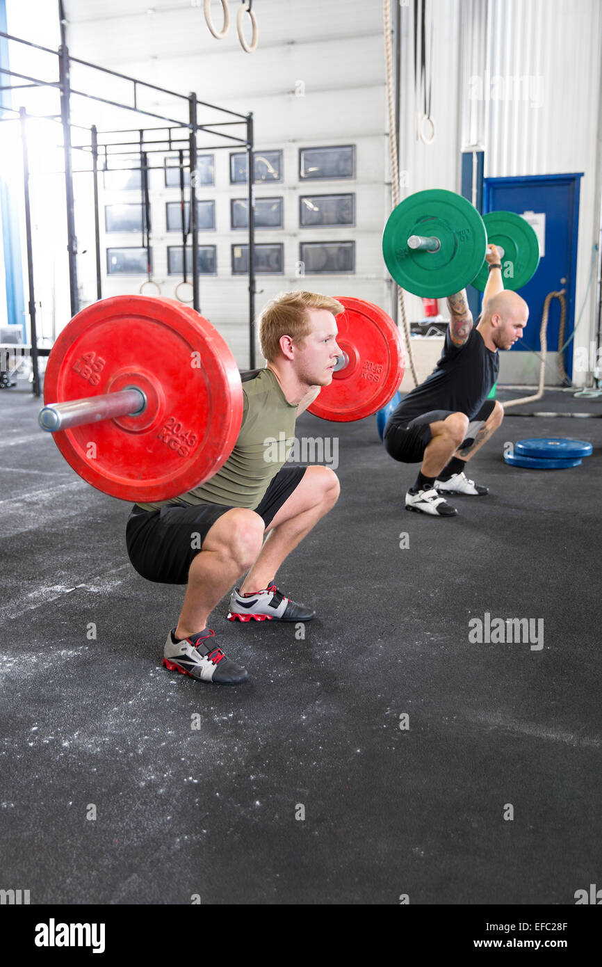 Team trains squats at fitness gym center Stock Photo
