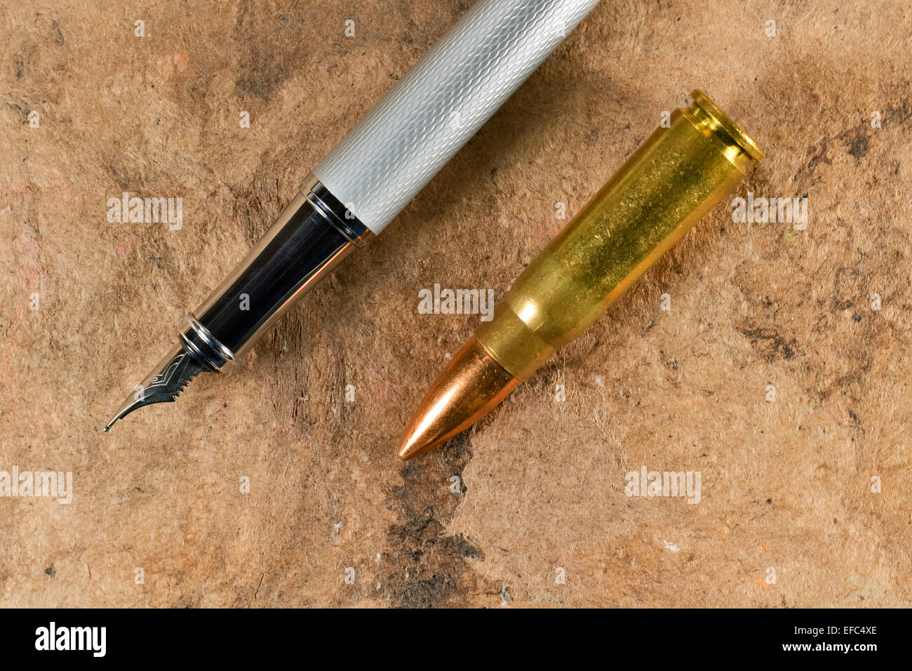 Fountain pen and a bullet in a parallel position on vintage background Stock Photo