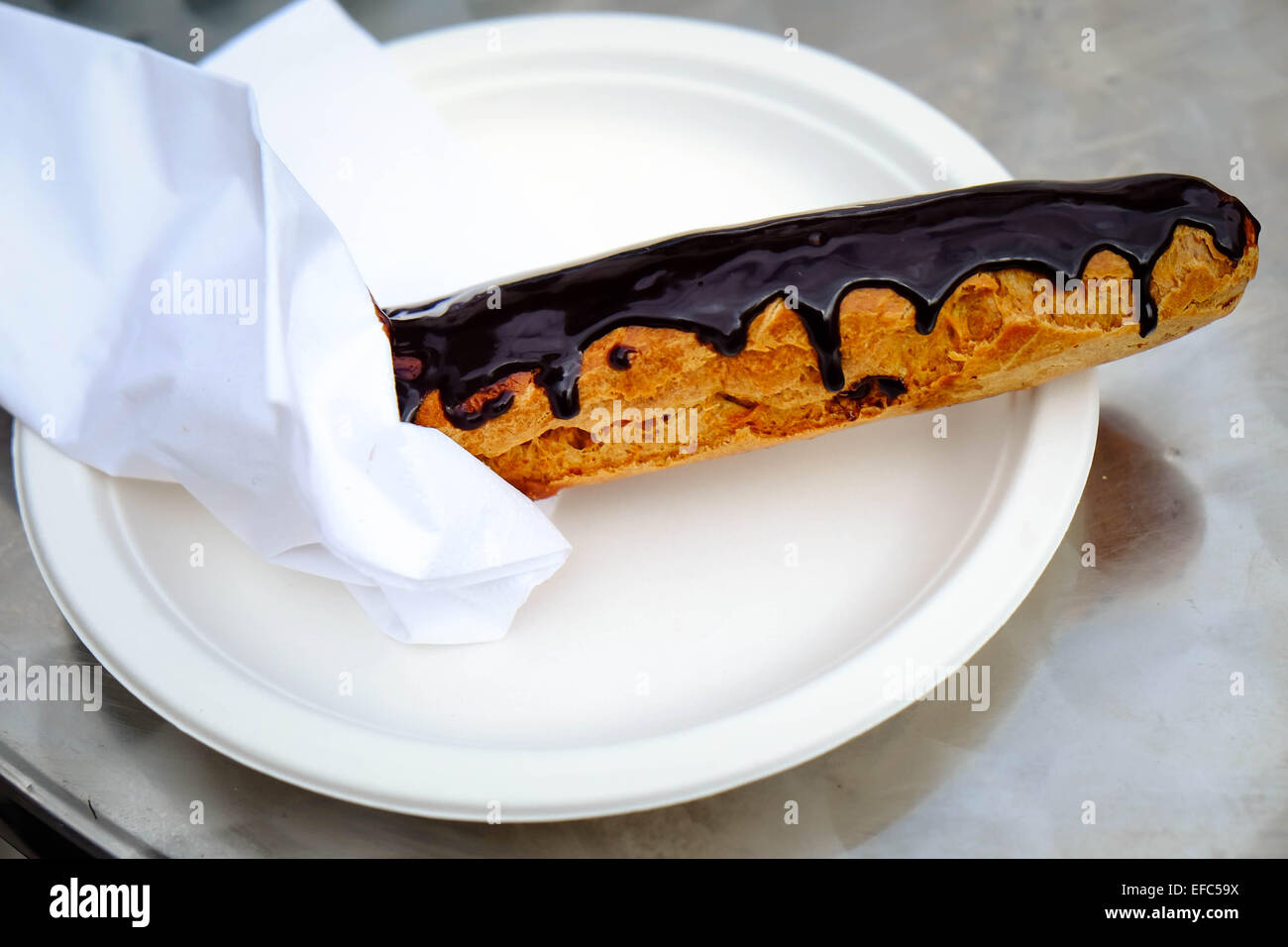 A single chocolate eclair on a white plate Stock Photo