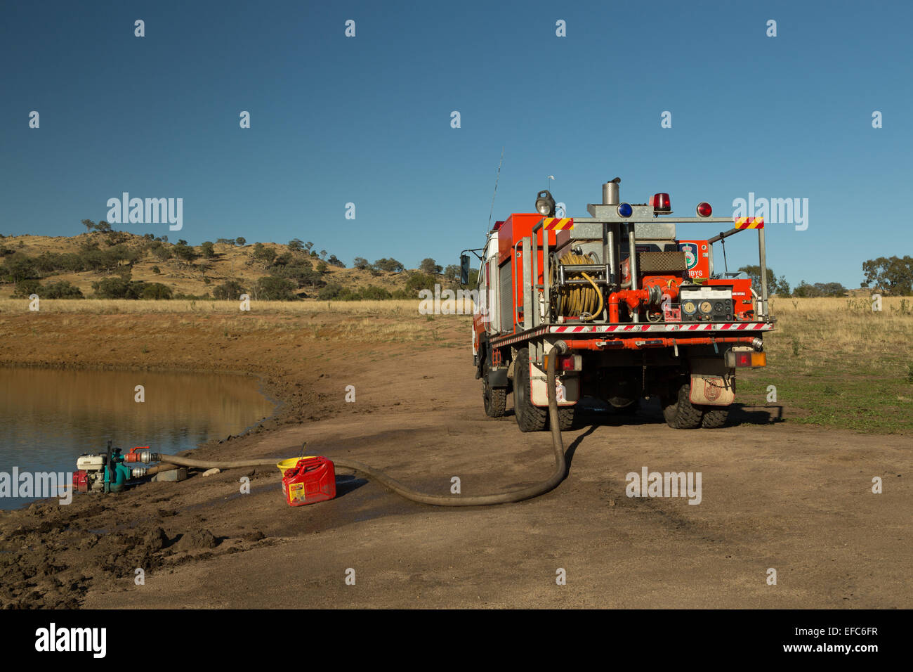 A photograph of the refilling of the water tanks of a fire truck in the aftermath of a bush fire on a dry Australian farm. Stock Photo