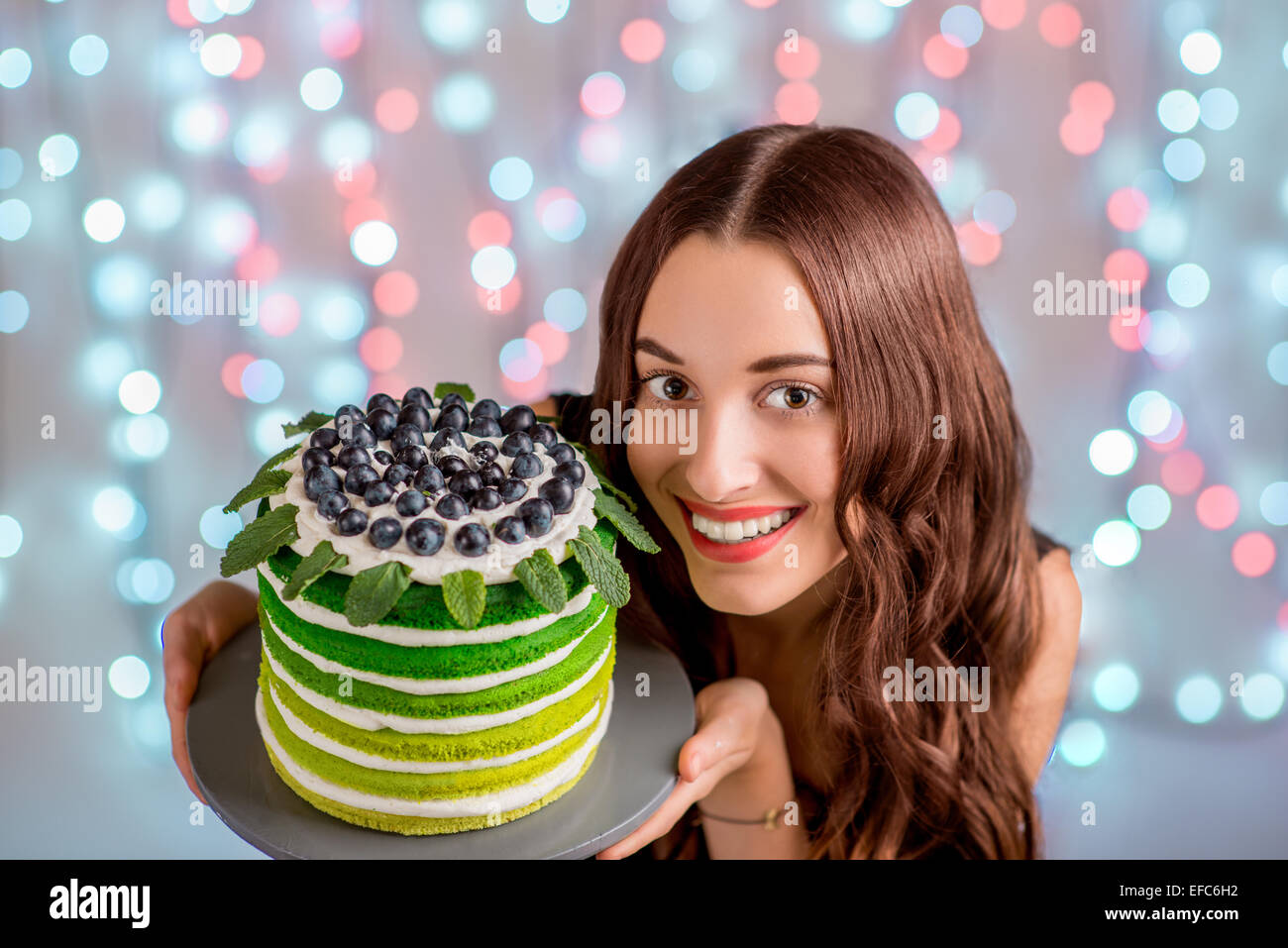 Beautiful girl holding happy birthday cake and smiling looking at ...