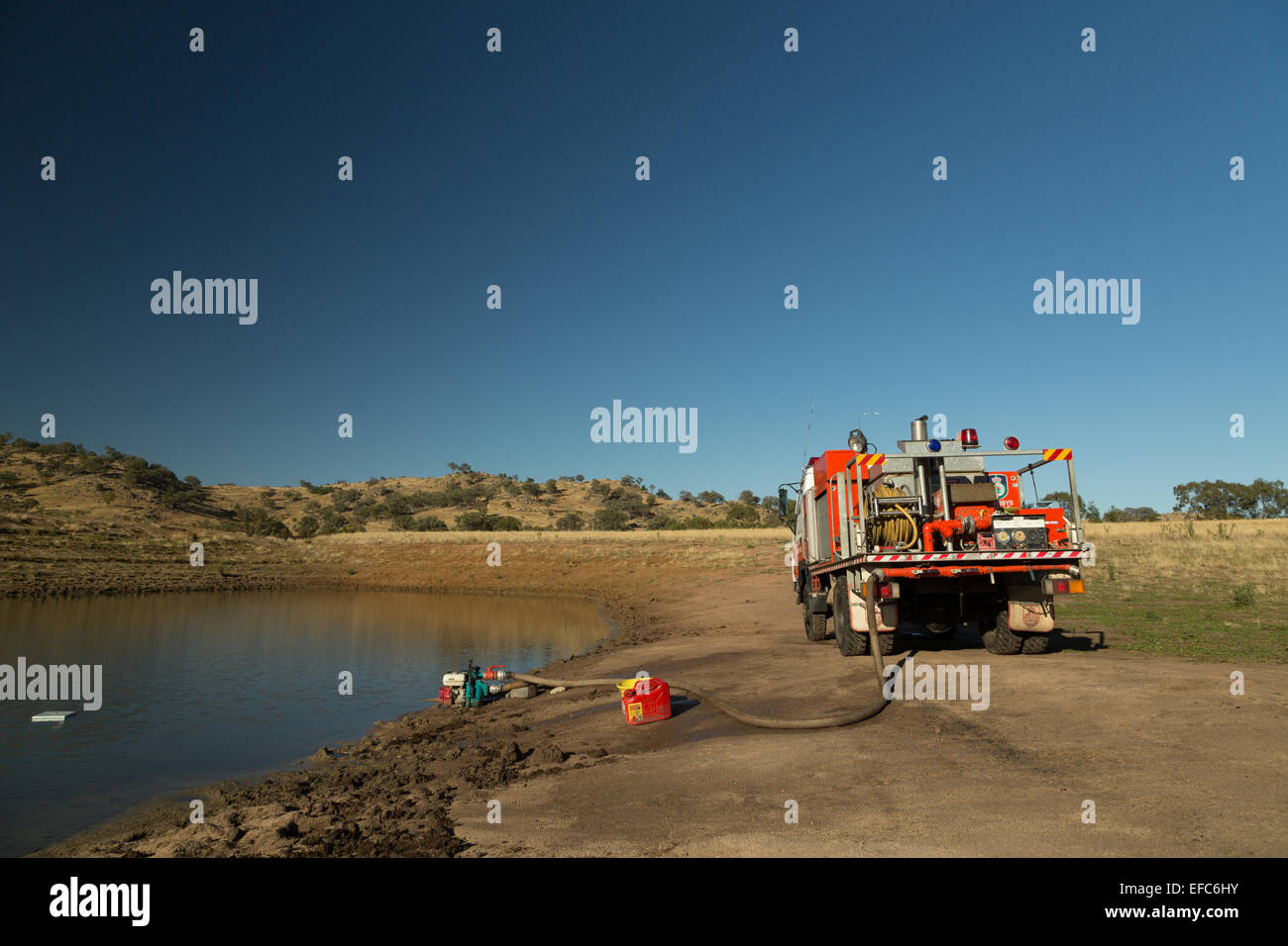 A photograph of the refilling of the water tanks of a fire truck in the aftermath of a bush fire on a dry Australian farm. Stock Photo