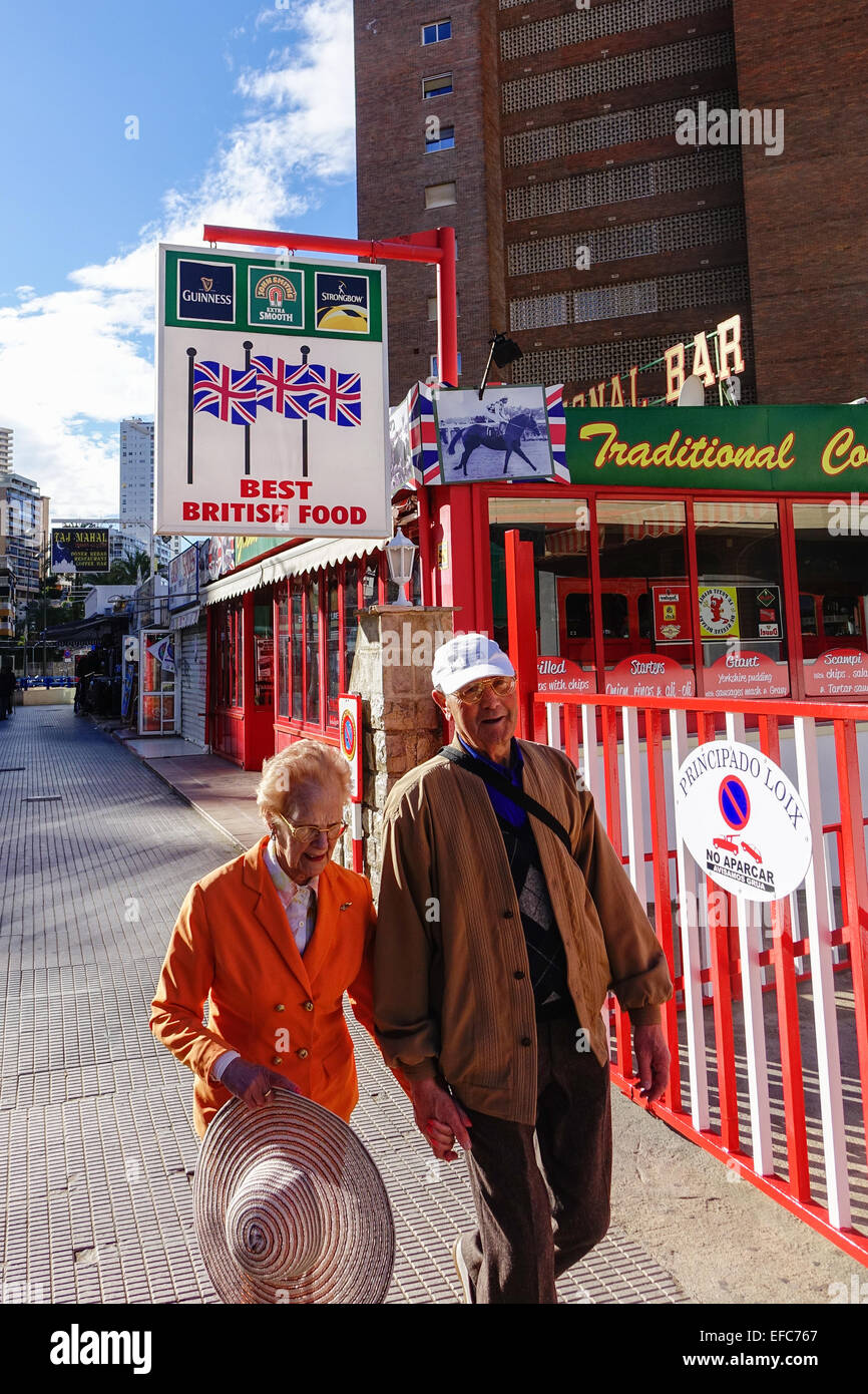 Senior couple walking down a street near British Bar in Benidorm, Costa Blanca, Spain Stock Photo