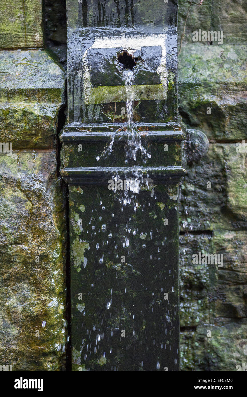 Damaged square section cast iron drain pipe leaking water Stock Photo