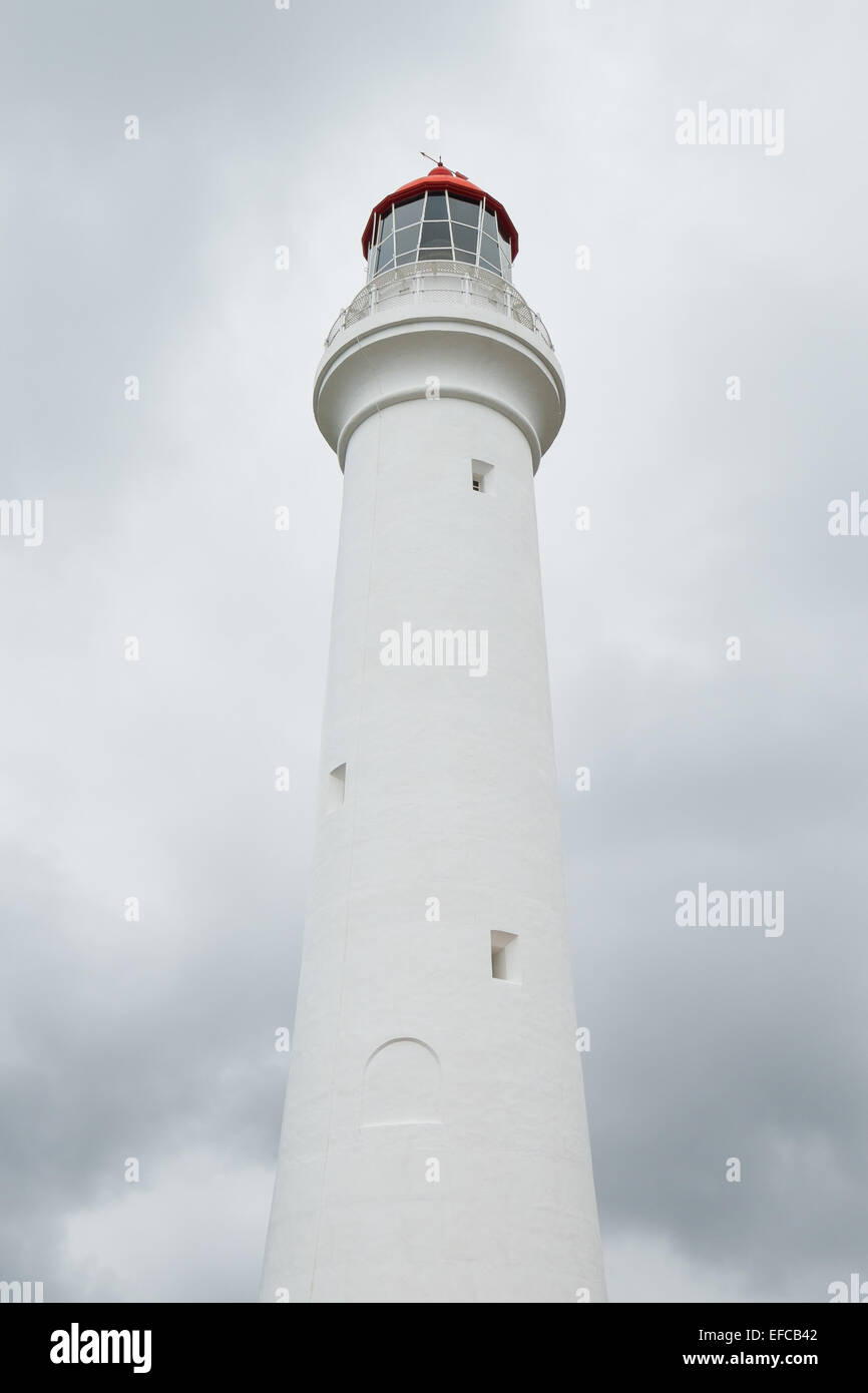 A light house with a red roof in front of stormy clouds. Stock Photo
