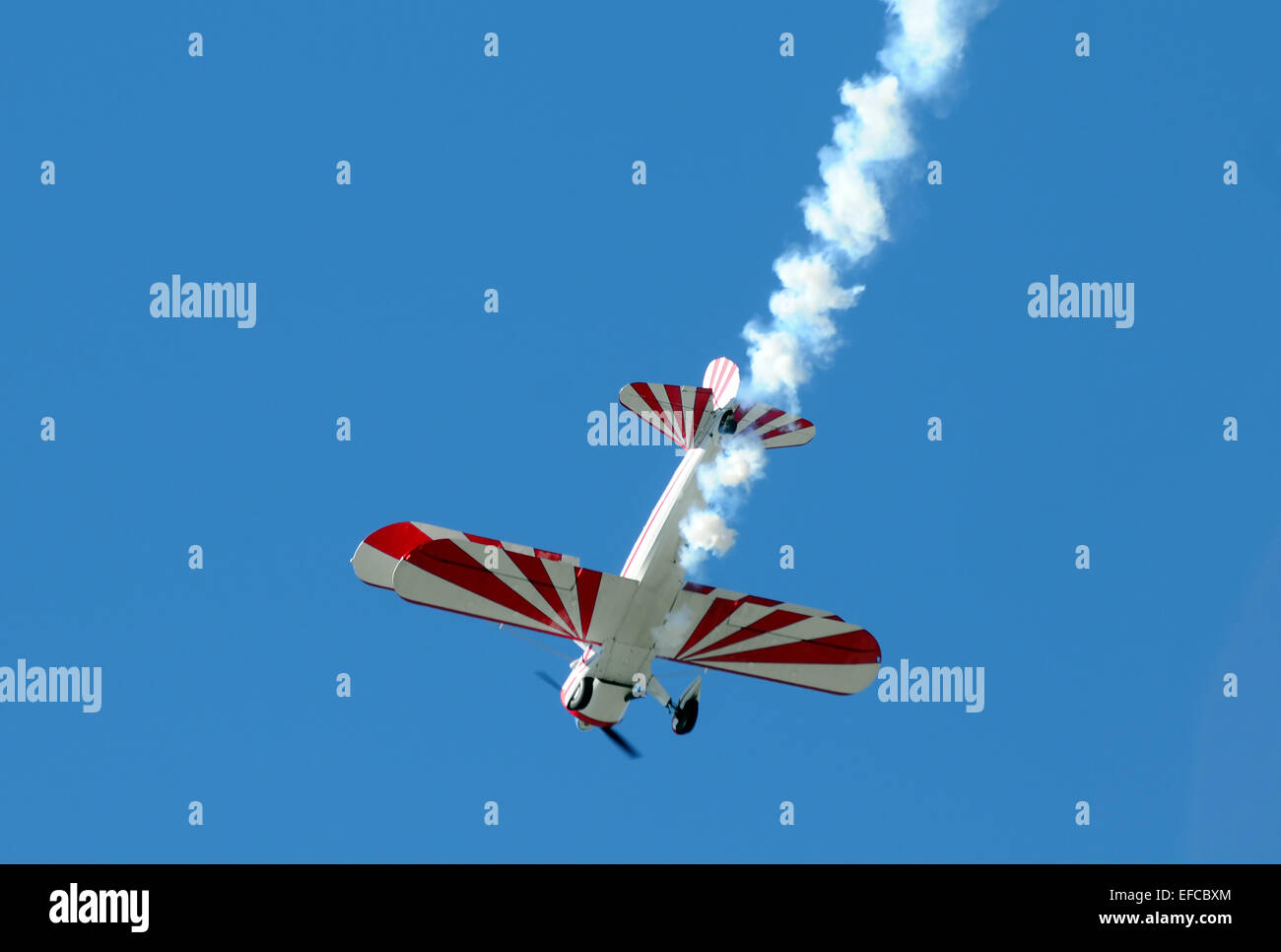 Retro biplane flying through the sky with smoke behind Stock Photo - Alamy