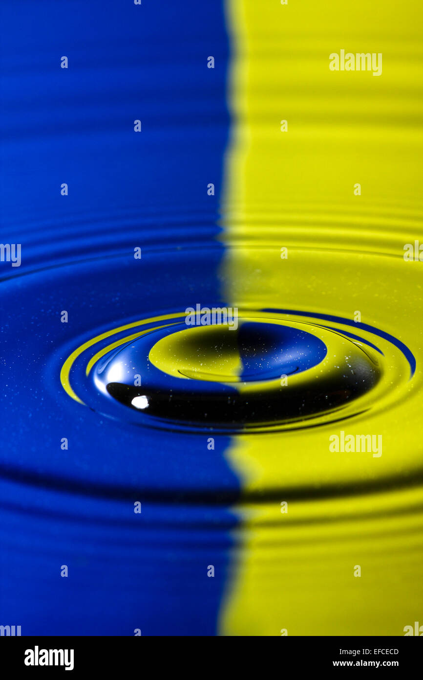 Water drop hitting the surface of water and rebounding with a colourful