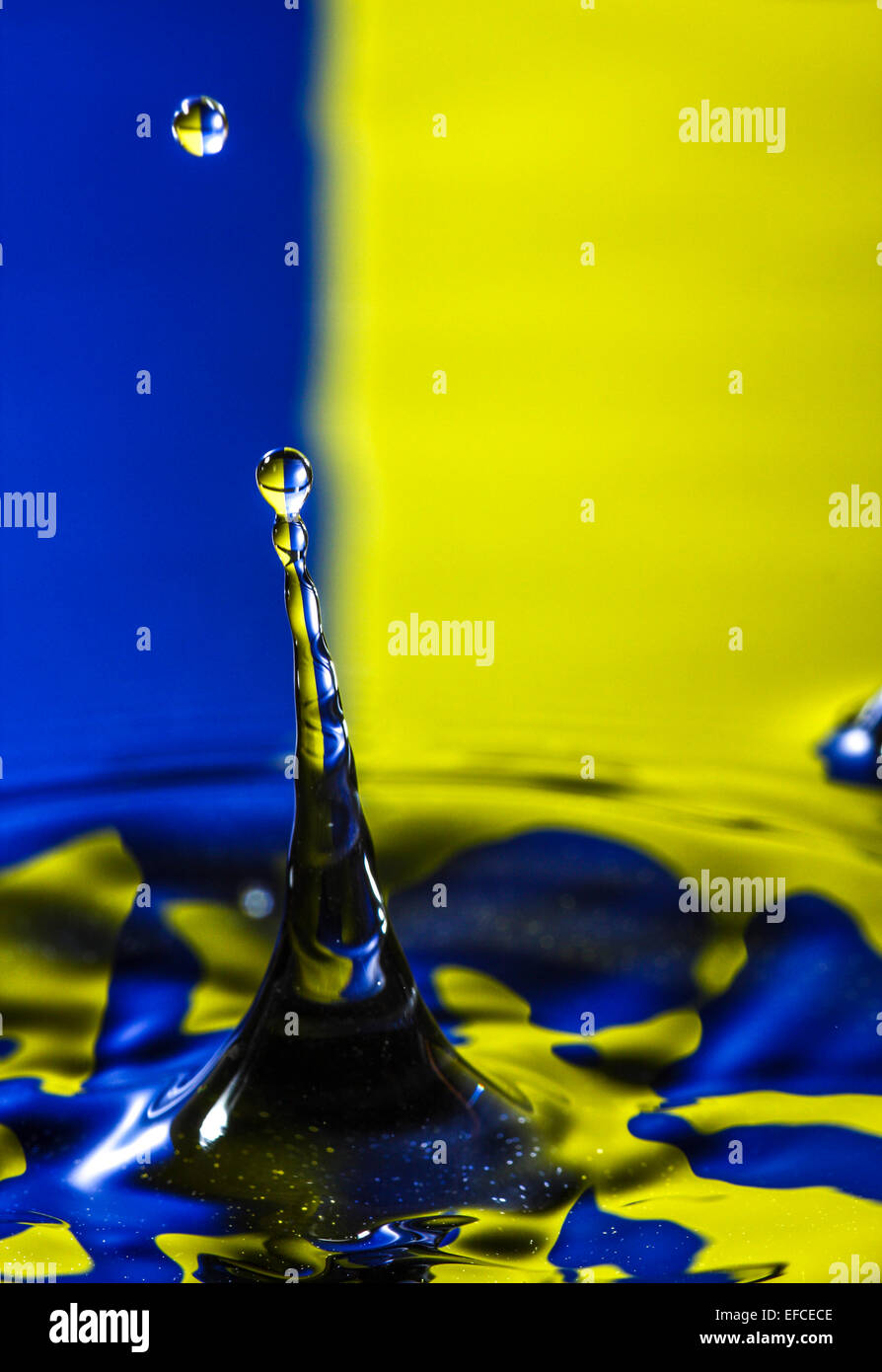 Water drop hitting the surface of water and rebounding with a colourful