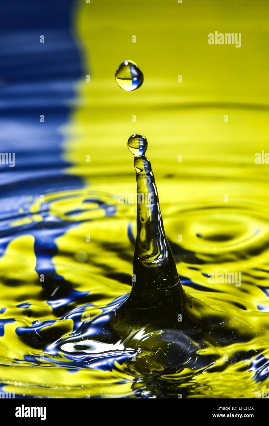 Water drop hitting the surface of water and rebounding with a colourful