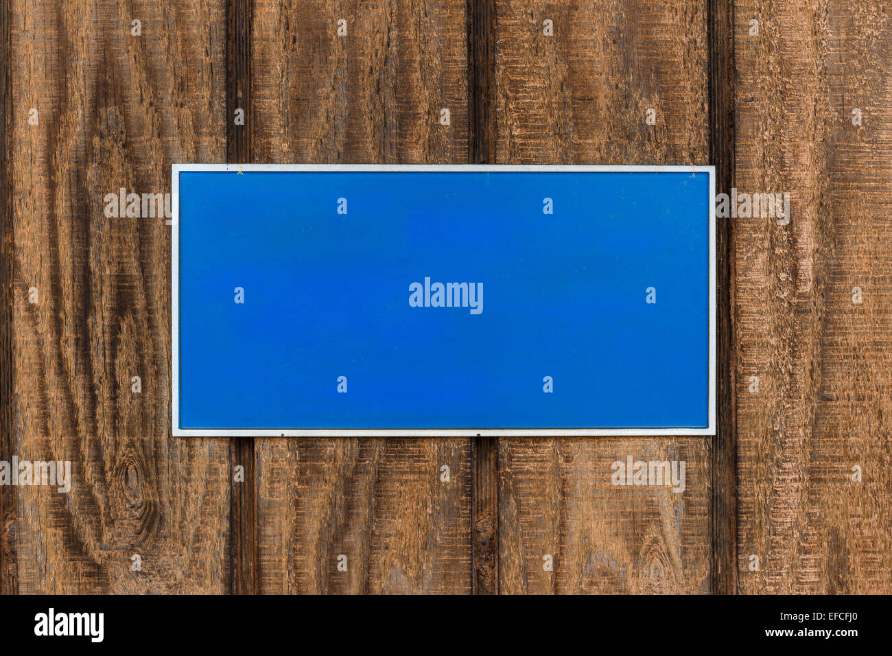 Empty blue Sign mounted on brown wooden wall. Stock Photo