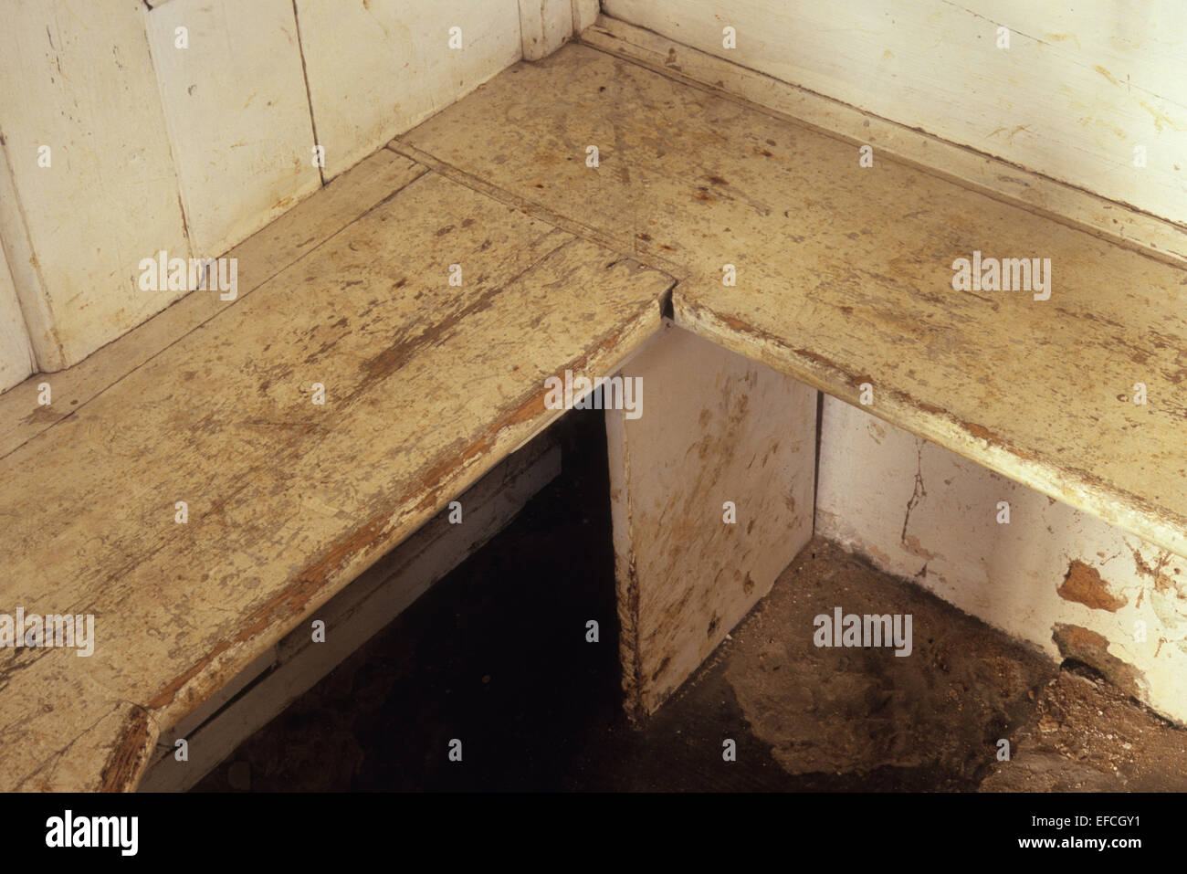 Corner of sports changing room with benches and wooden walls painted white but worn and neglected Stock Photo