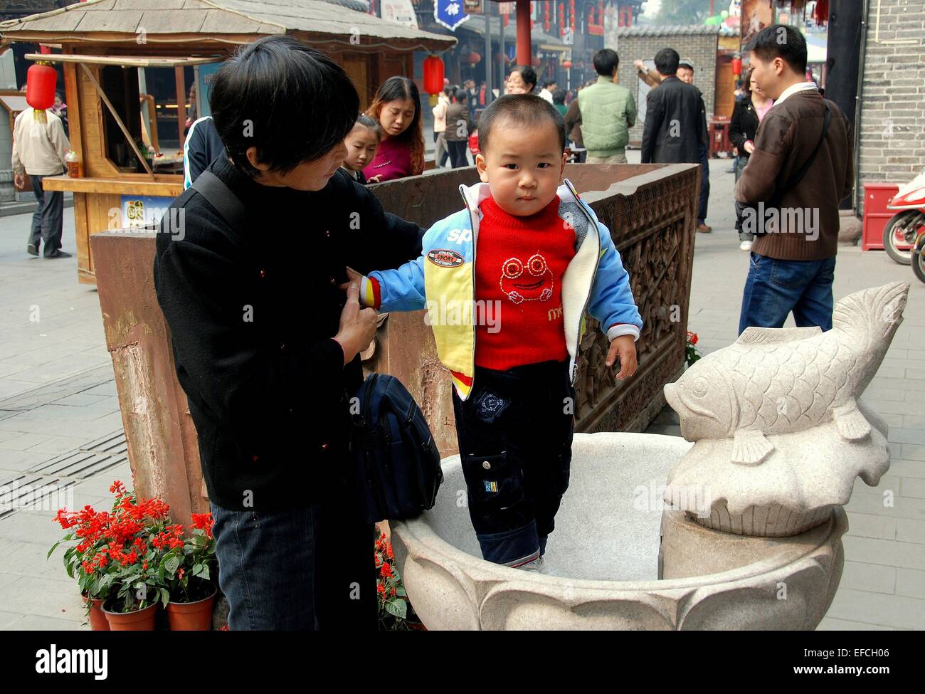 Chengdu, China: A little boy standing in a fish fountain basin held by ...