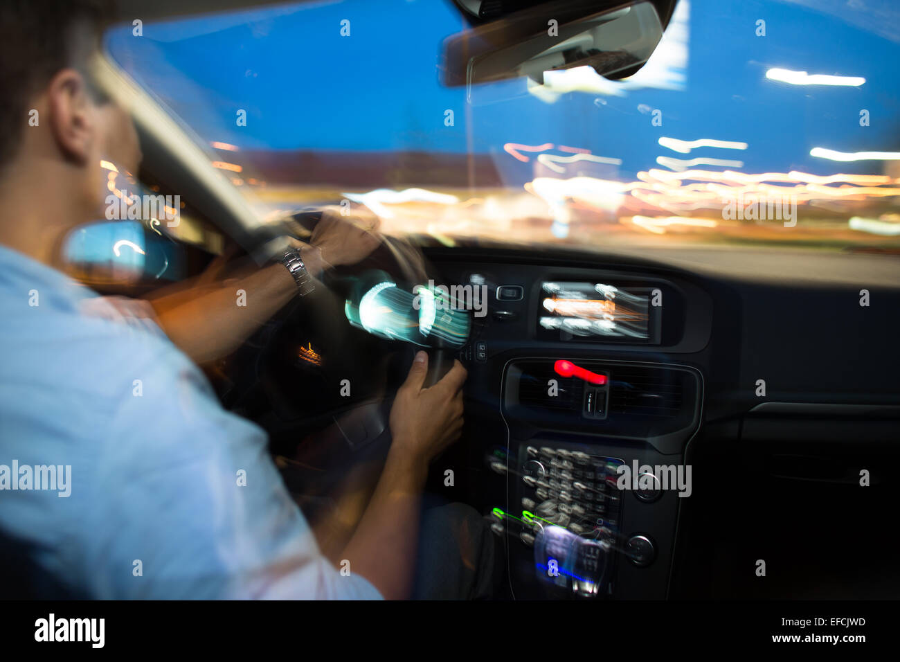 Driving a car at night - young man driving his modern car at night in a ...