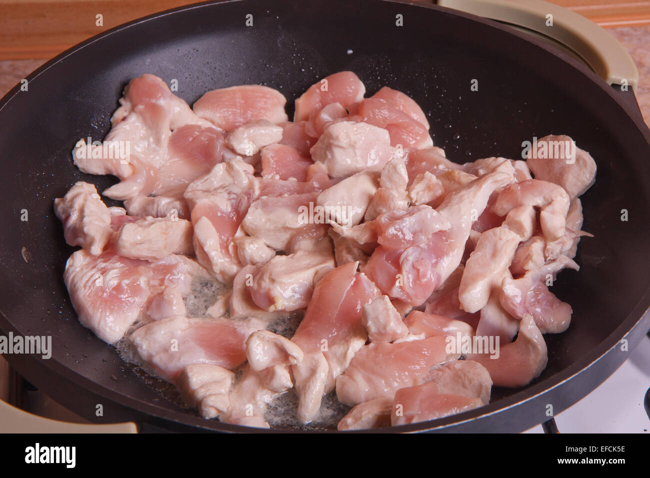 Cutted chicken meet is fried on a deep frying pan. Stock Photo