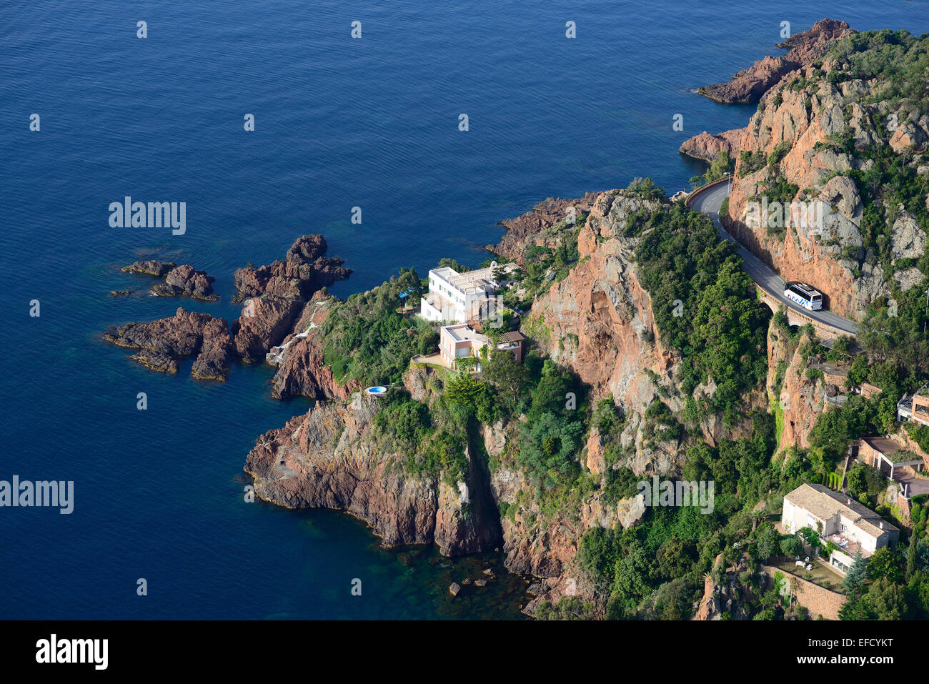 AERIAL VIEW. Sightseeing bus on a scenic corniche. Pointe de la Paume, Théoule-sur-Mer, Esterel Massif, Alpes-Maritimes, French Riviera, France. Stock Photo