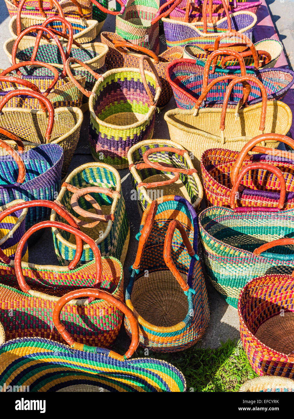 A brightly colored display of handmade baskets from Africa on a sidewalk by the Saturday farmer's market in Santa Barbara, CA. Stock Photo