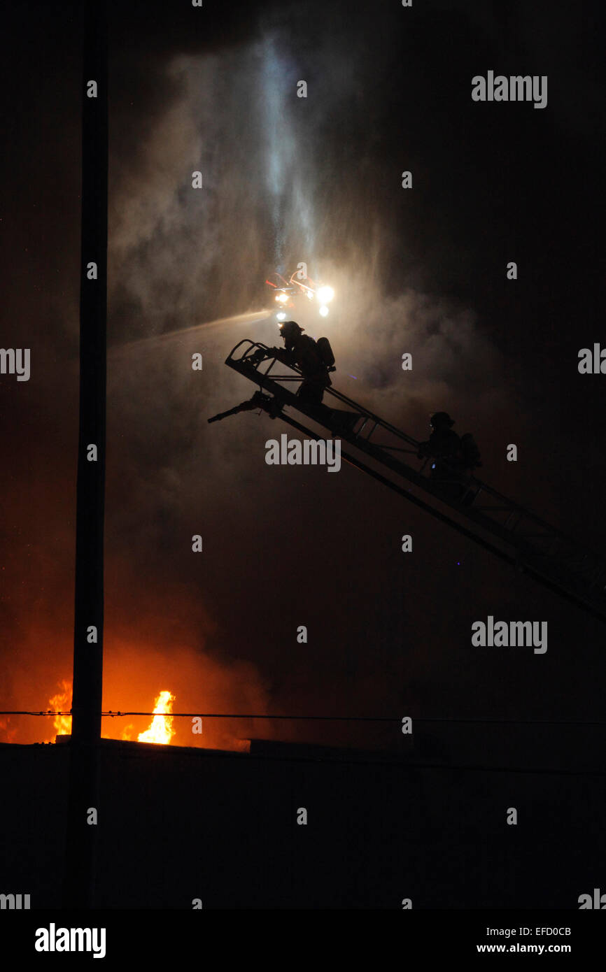Firefighters prepare to battle a fire from above. Stock Photo