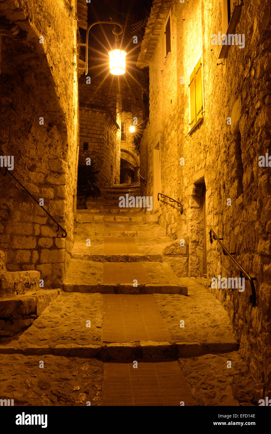 Illuminated alley in the night in a medieval village. Èze-Village, Alpes-Maritimes, French Riviera, France. Stock Photo