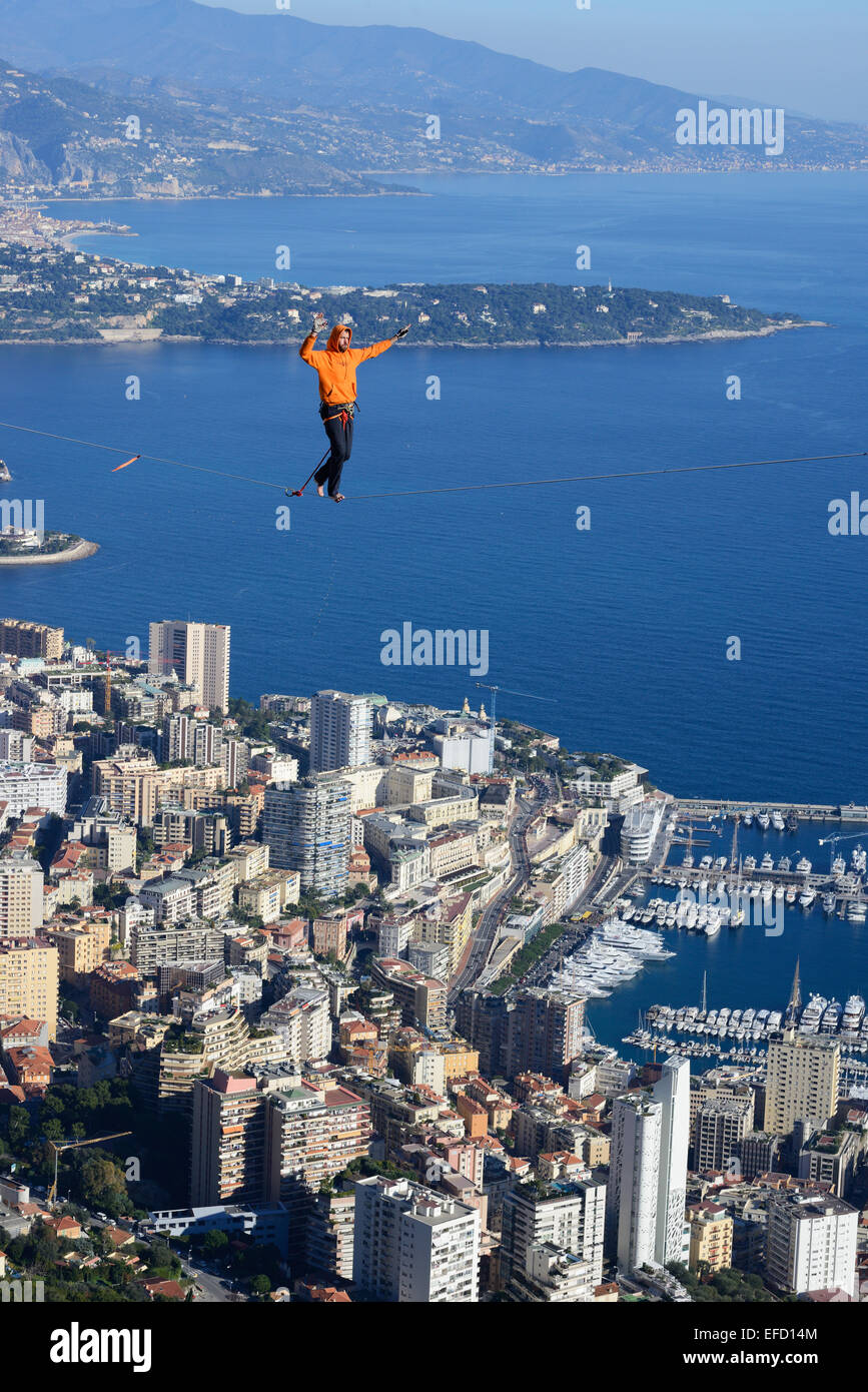 Young man highlining (slacklining) at an elevation of 550 meters Above Sea Level. Principality of Monaco in the distance. La Turbie, France. Stock Photo