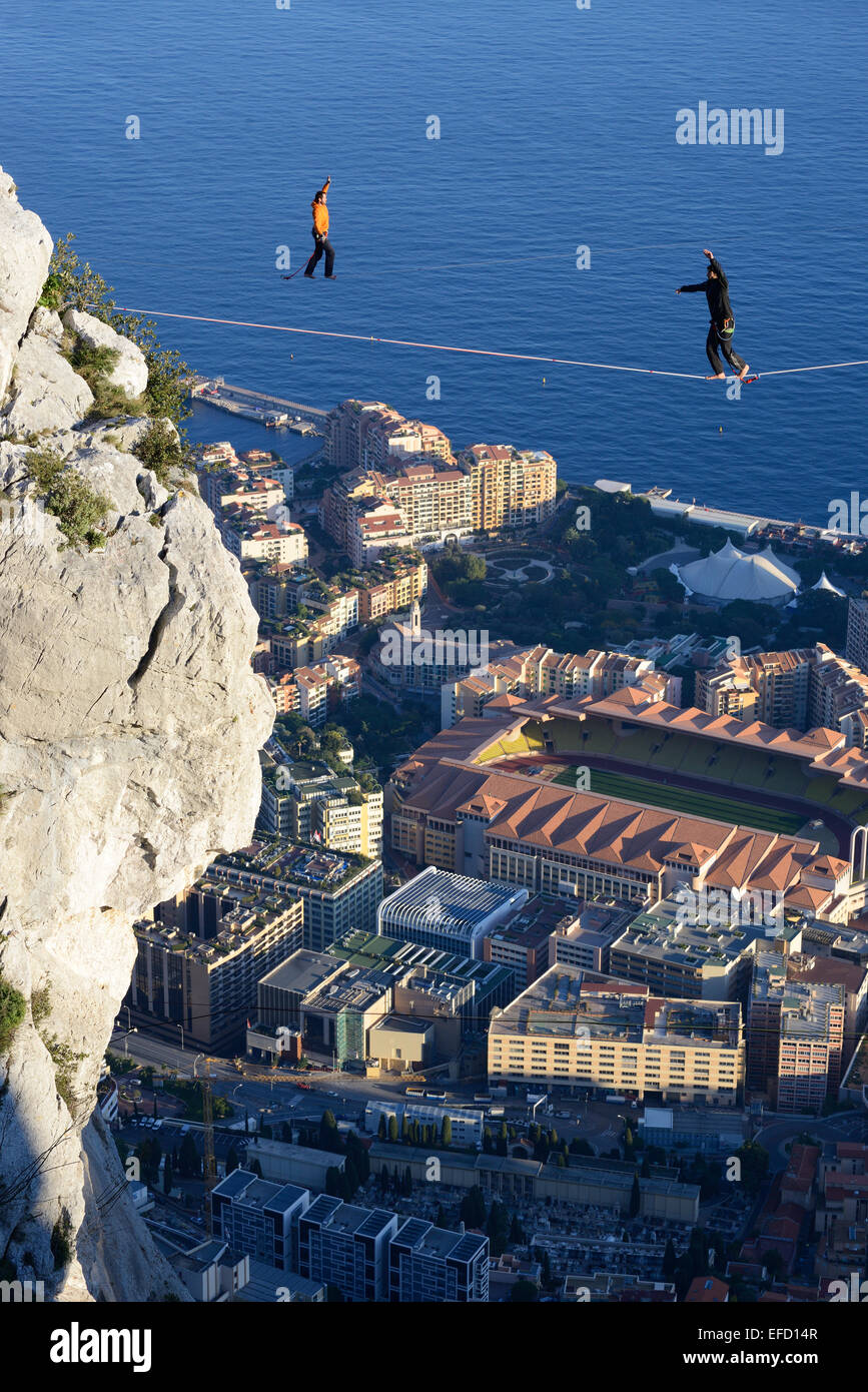 Two men highlining (slacklining) at an elevation of 550 meters above sea level. Below them, the Fontvieille District in the Principality of Monaco. Stock Photo