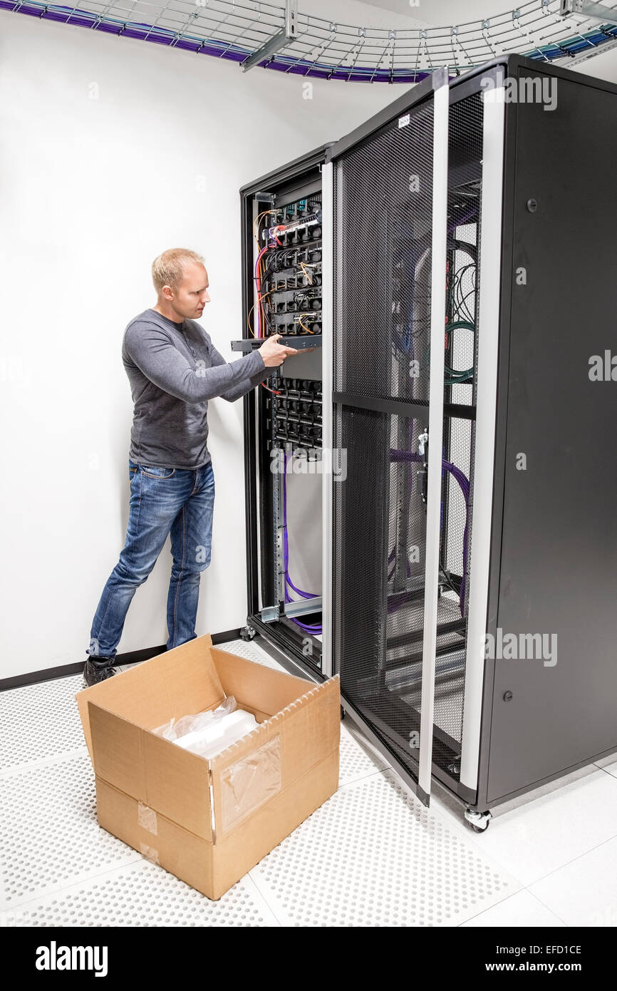 IT engineer installs network switch in datacenter Stock Photo