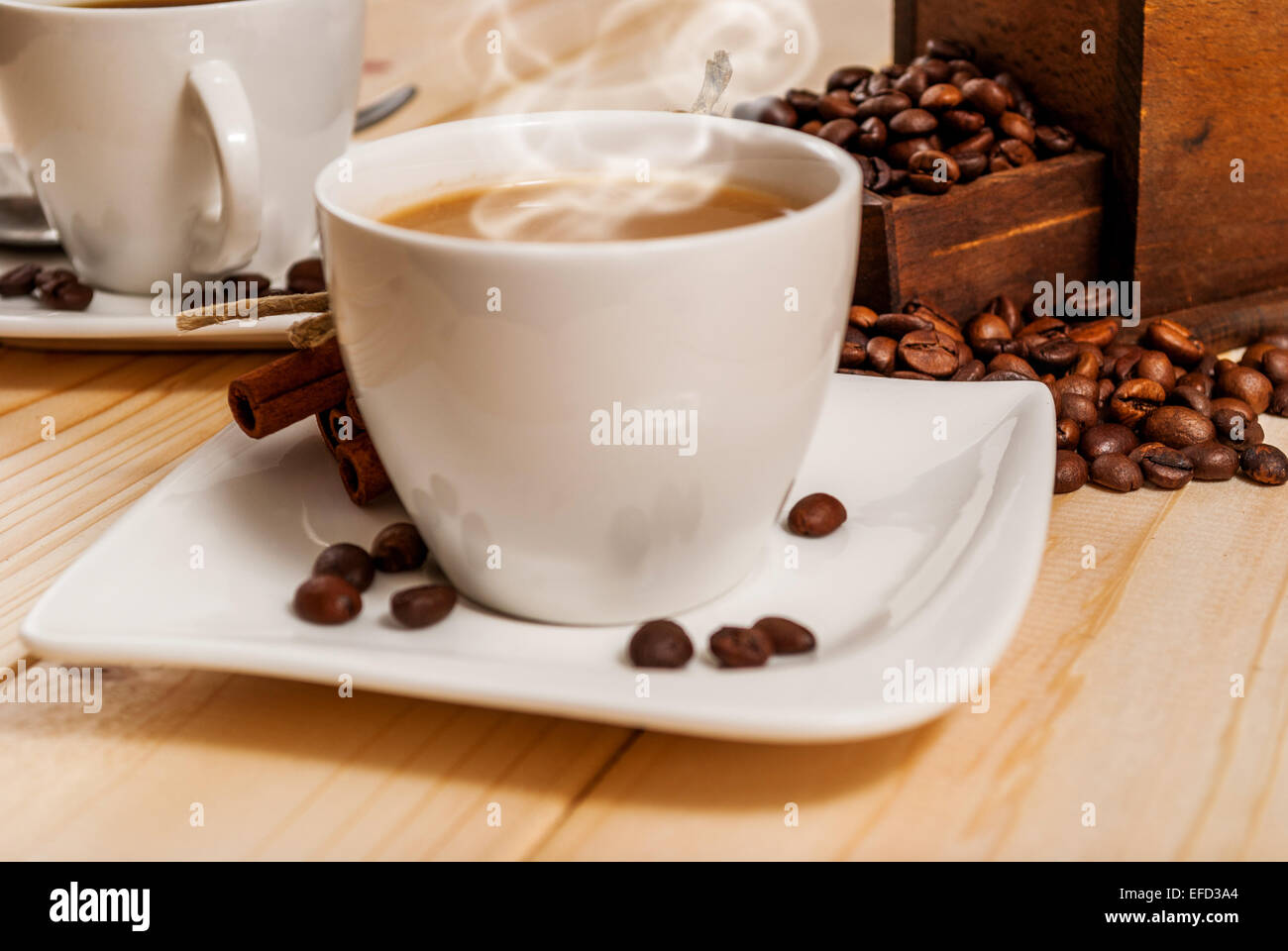 Cup of white coffee and cinnamon and ancient grinder on wood table Stock Photo