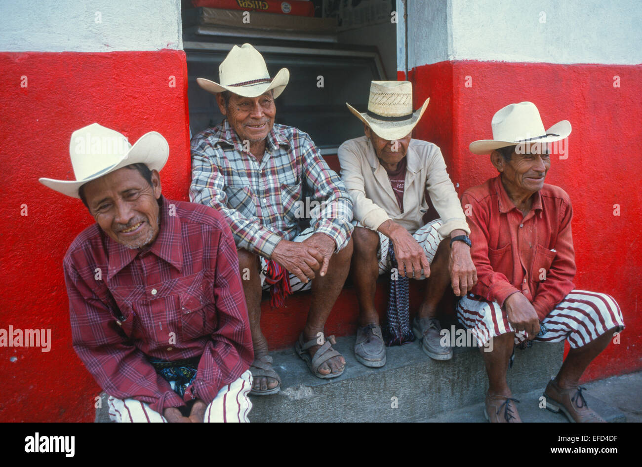 A group of men in traditional dress remain seated in one of the streets of Chichicastenango Stock Photo