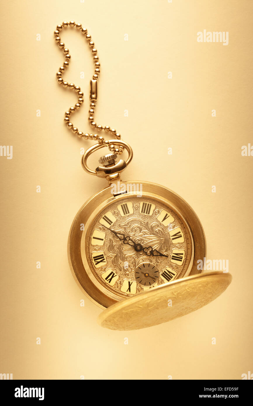 Golden pocket watch with chain on beige background Stock Photo