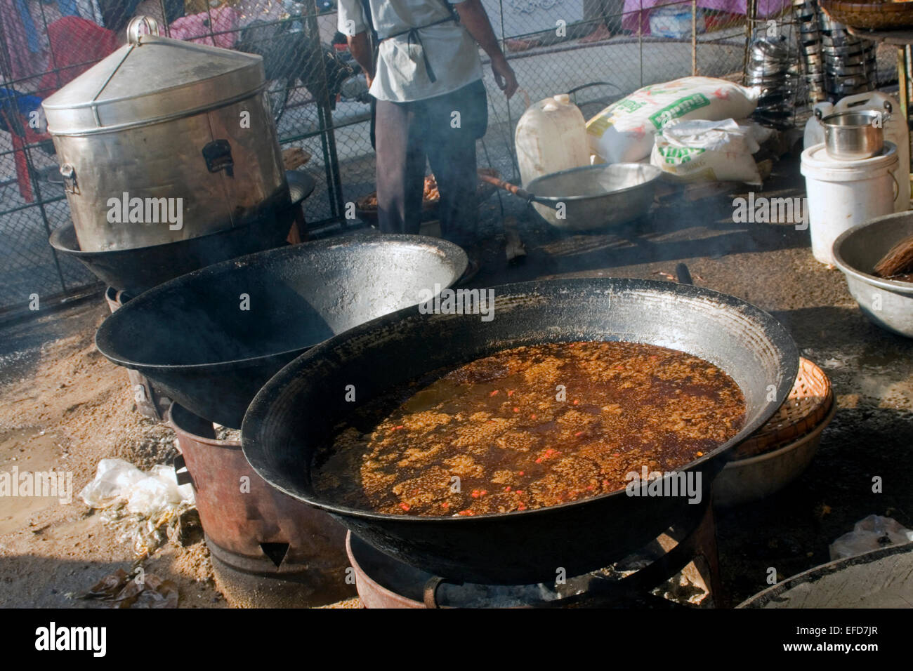 Broth used to spice street food is cooking in a large vat on a city