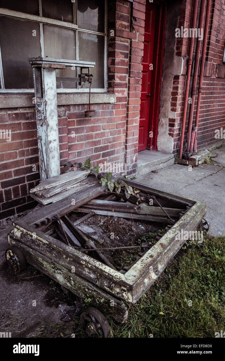 An abandoned scale sits outside a doorway of a red brick building. Stock Photo
