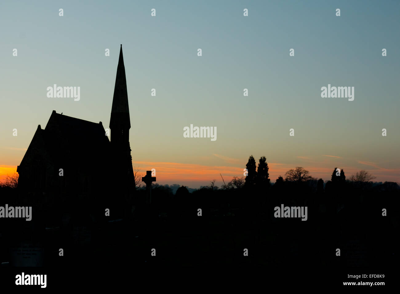 Silhouette of a church and grave yard at sunset Stock Photo