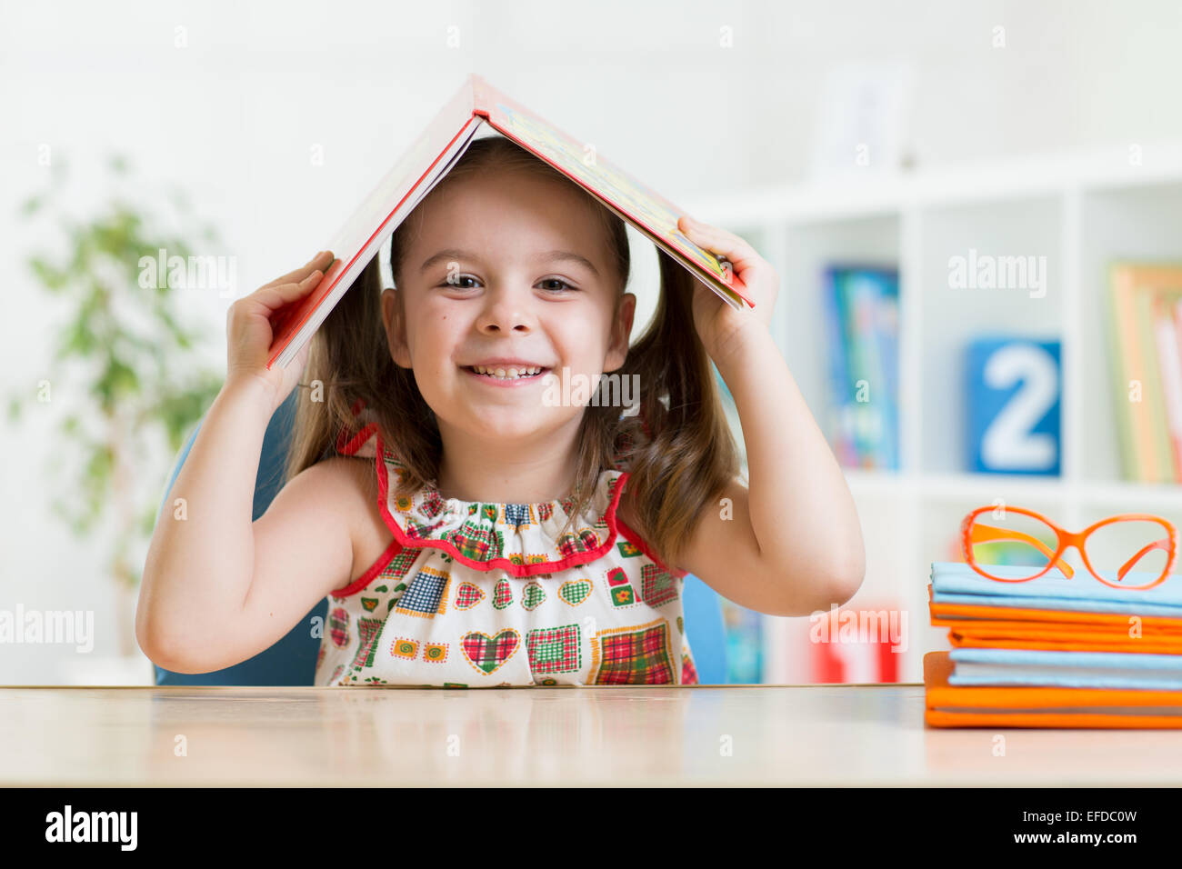 preschooler child girl with book over her head Stock Photo - Alamy