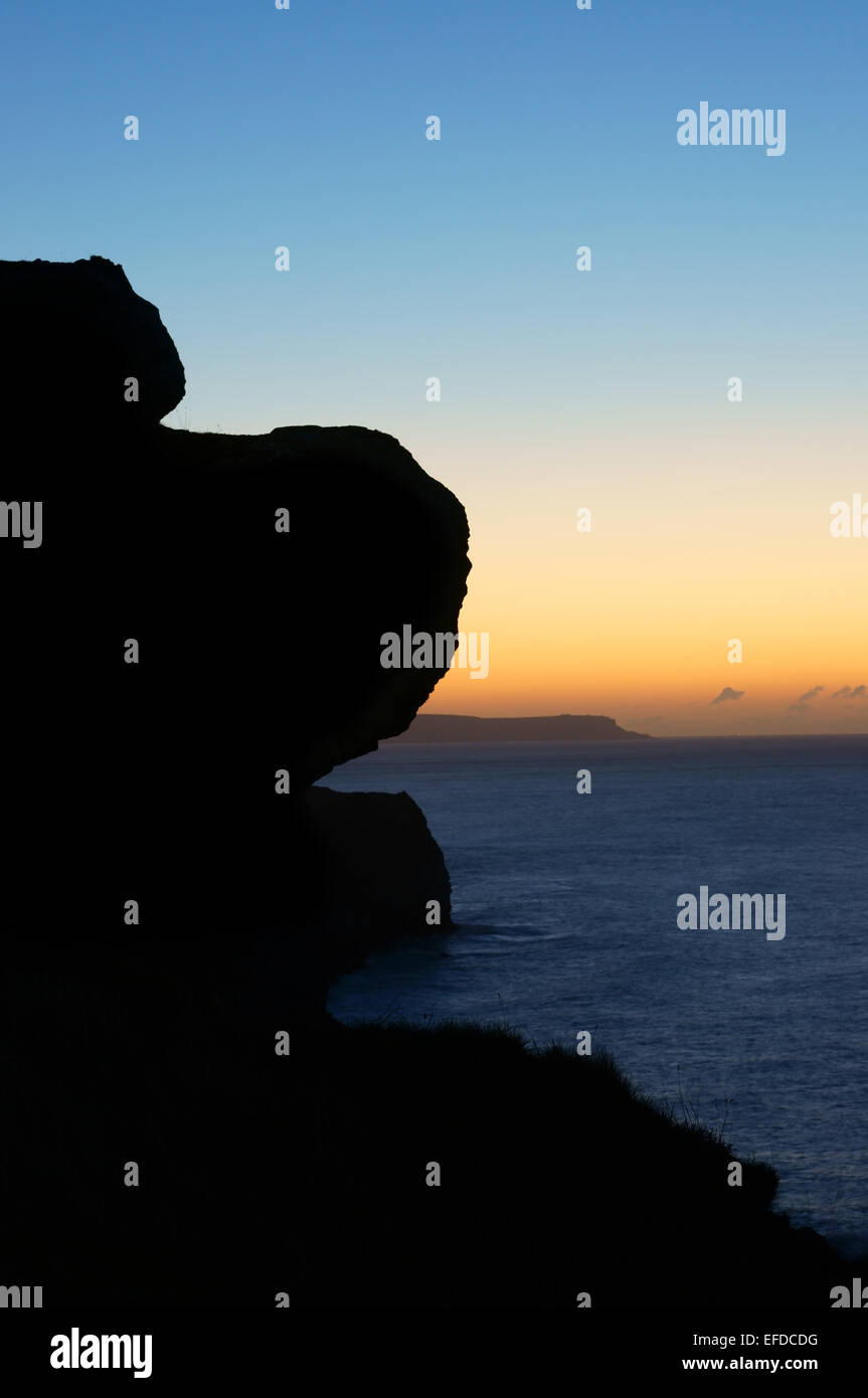 Sunrise over St Aldhelm's head, the rocks of Dungy Head silhouetted in the foreground. Stock Photo