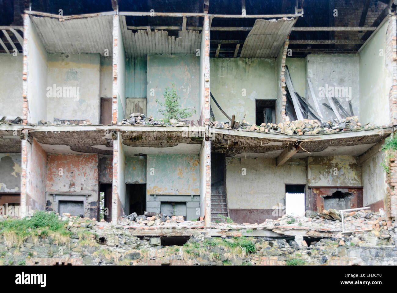 Front wall of a building collapses and falls away, exposing the rooms of flats/a[artments behind. Stock Photo