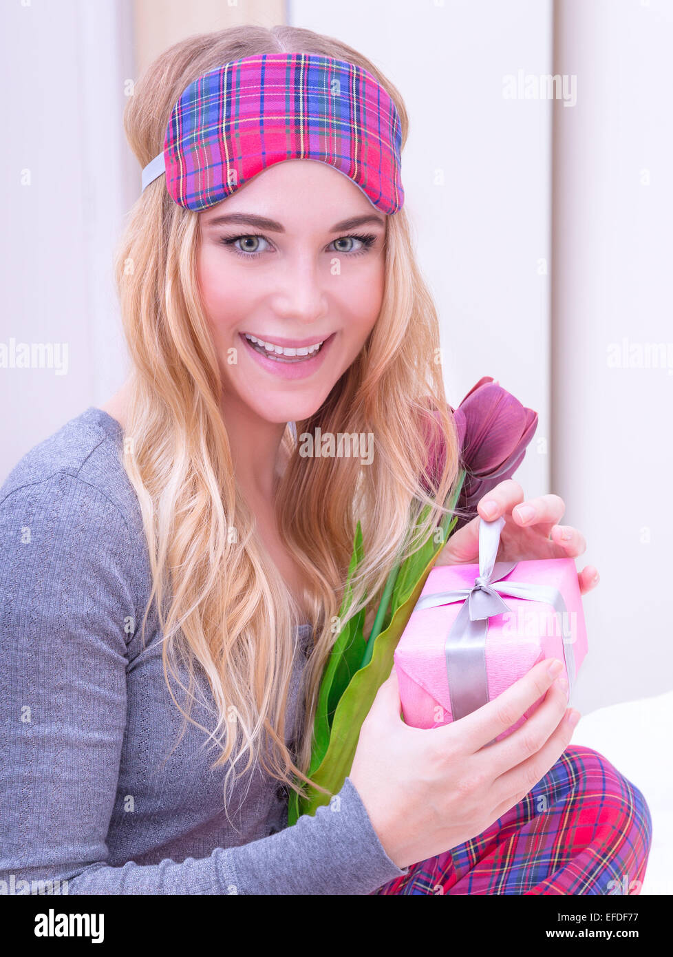 Closeup portrait of happy excited girl in the morning sitting on the bed and open gift box, enjoying romantic holiday Stock Photo