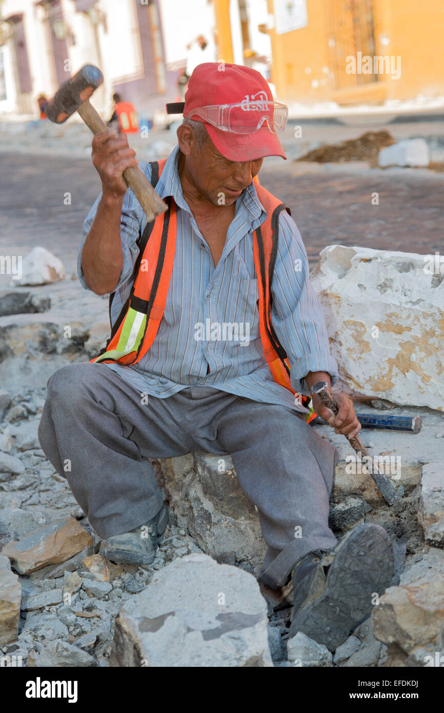 Oaxaca, Mexico - Workers use hammers and chisels to rebuild a cobblestone street. Stock Photo