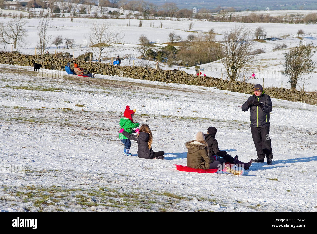 Lake District, Cumbria, UK. 1st February, 2015. UK Weather: After the recent snowfall, on a sunny but bitterly cold day, families enjoy sledging on the fells near Caldbeck, the Lake District, Cumbria, England UK. Credit:  Julie Fryer/Alamy Live News Stock Photo