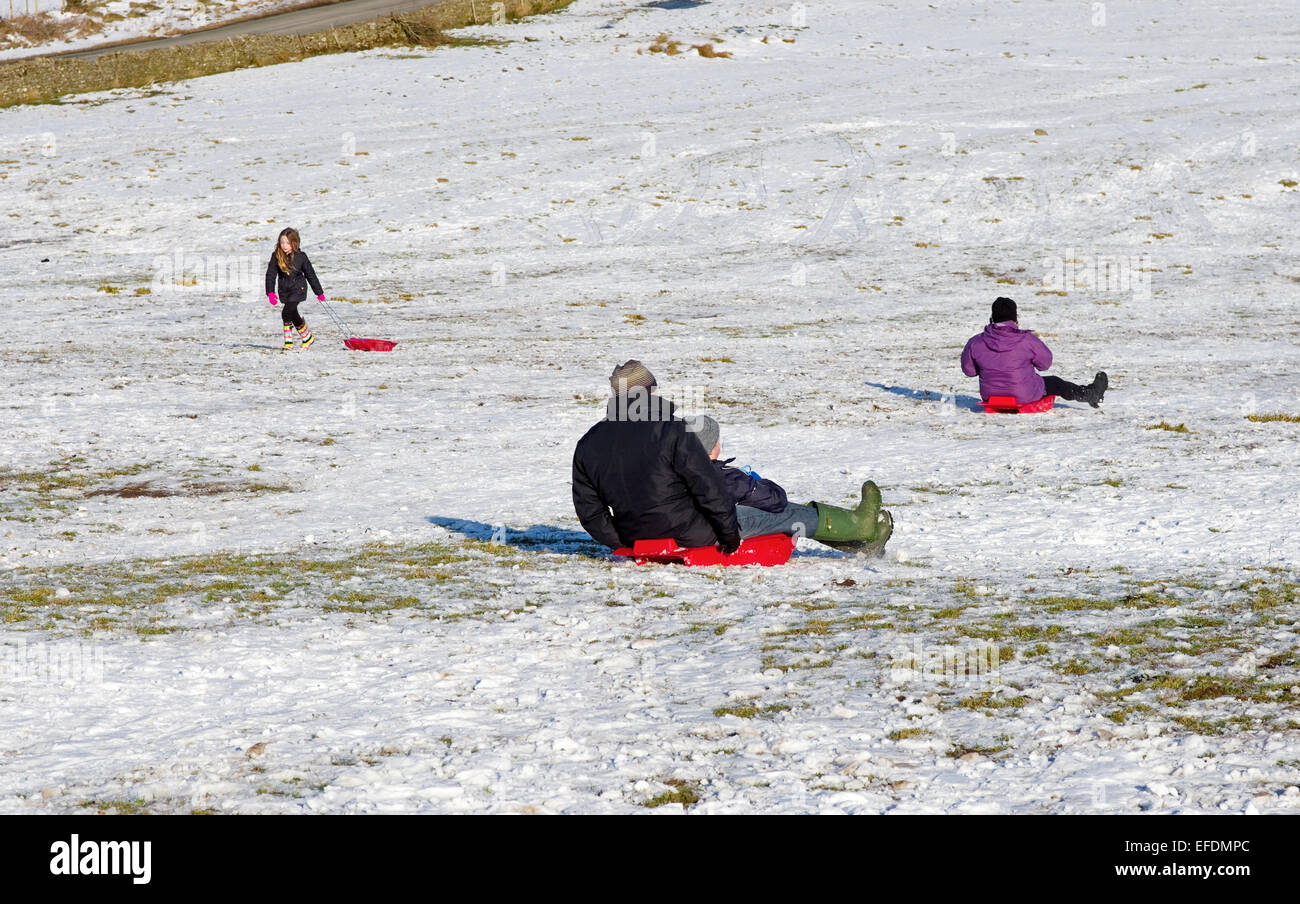 Lake District, Cumbria, UK. 1st February, 2015. UK Weather: After the recent snowfall, on a sunny but bitterly cold day, families enjoy sledging on the fells near Caldbeck, the Lake District, Cumbria, England UK. Credit:  Julie Fryer/Alamy Live News Stock Photo