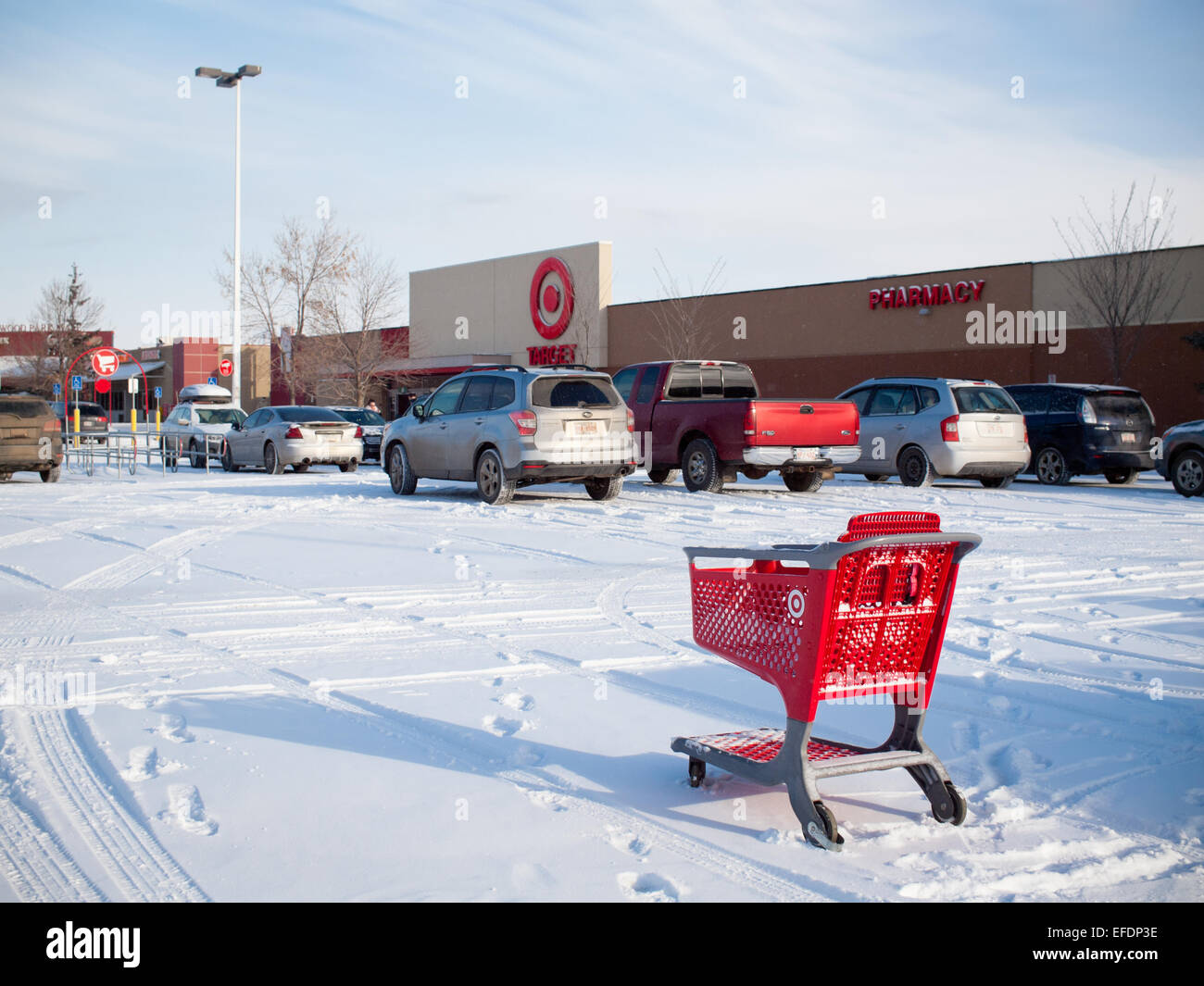 A shopping cart in the snow in the parking lot of a Target Canada store