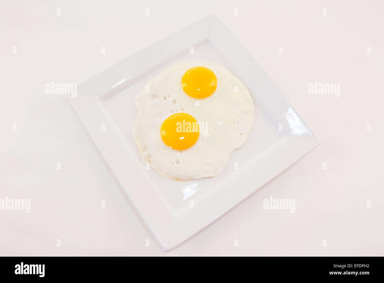 Two fried eggs on a white plate Stock Photo