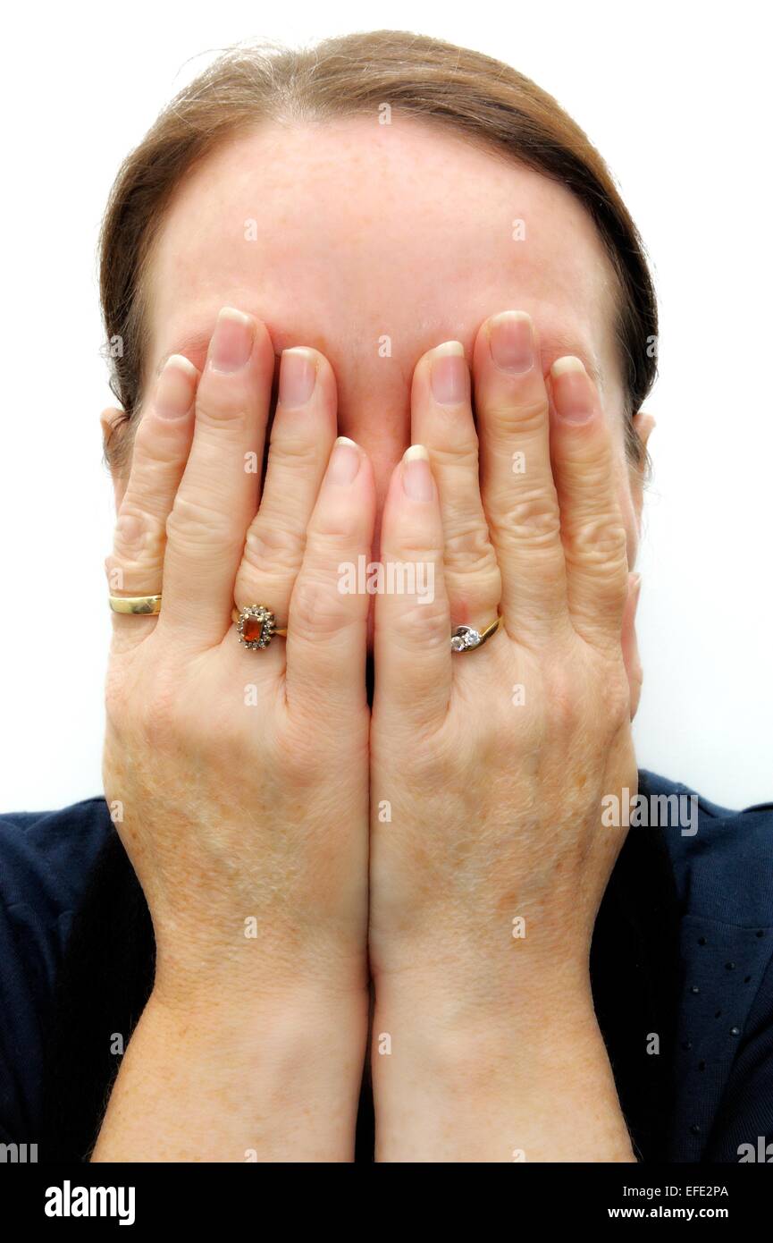 A white adult female hiding her face using both hands Stock Photo