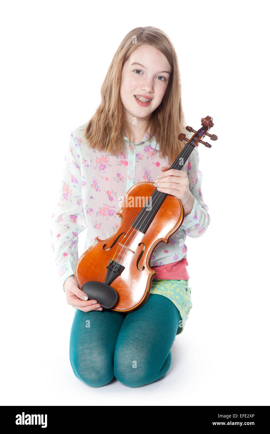 young girl sits in studio against white background and holds violin ...