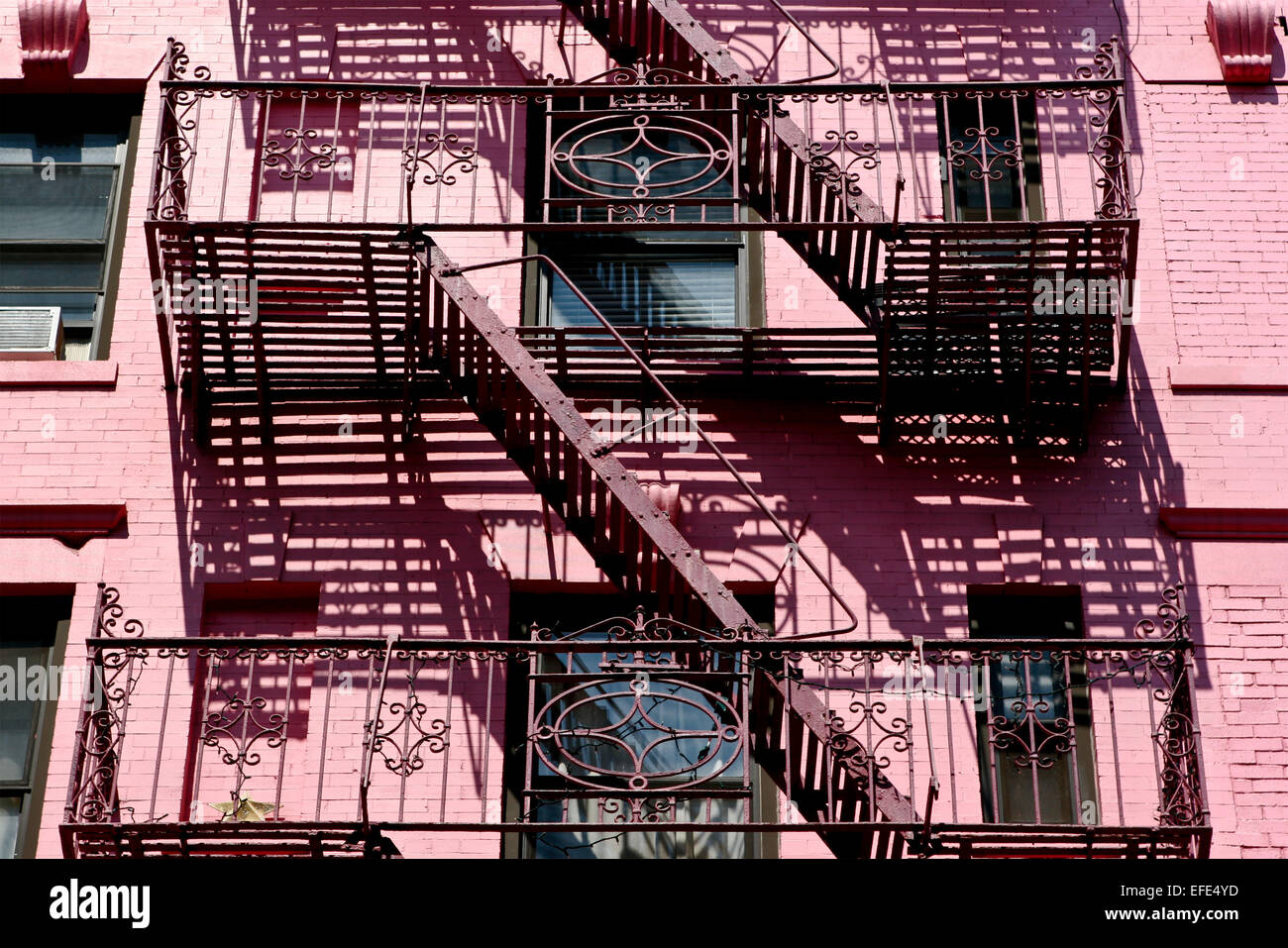Facade of a pink building with emergency stairs with handrail, ladders fire escape. Soho, Manhattan, New York City, NY, United States of America, USA Stock Photo