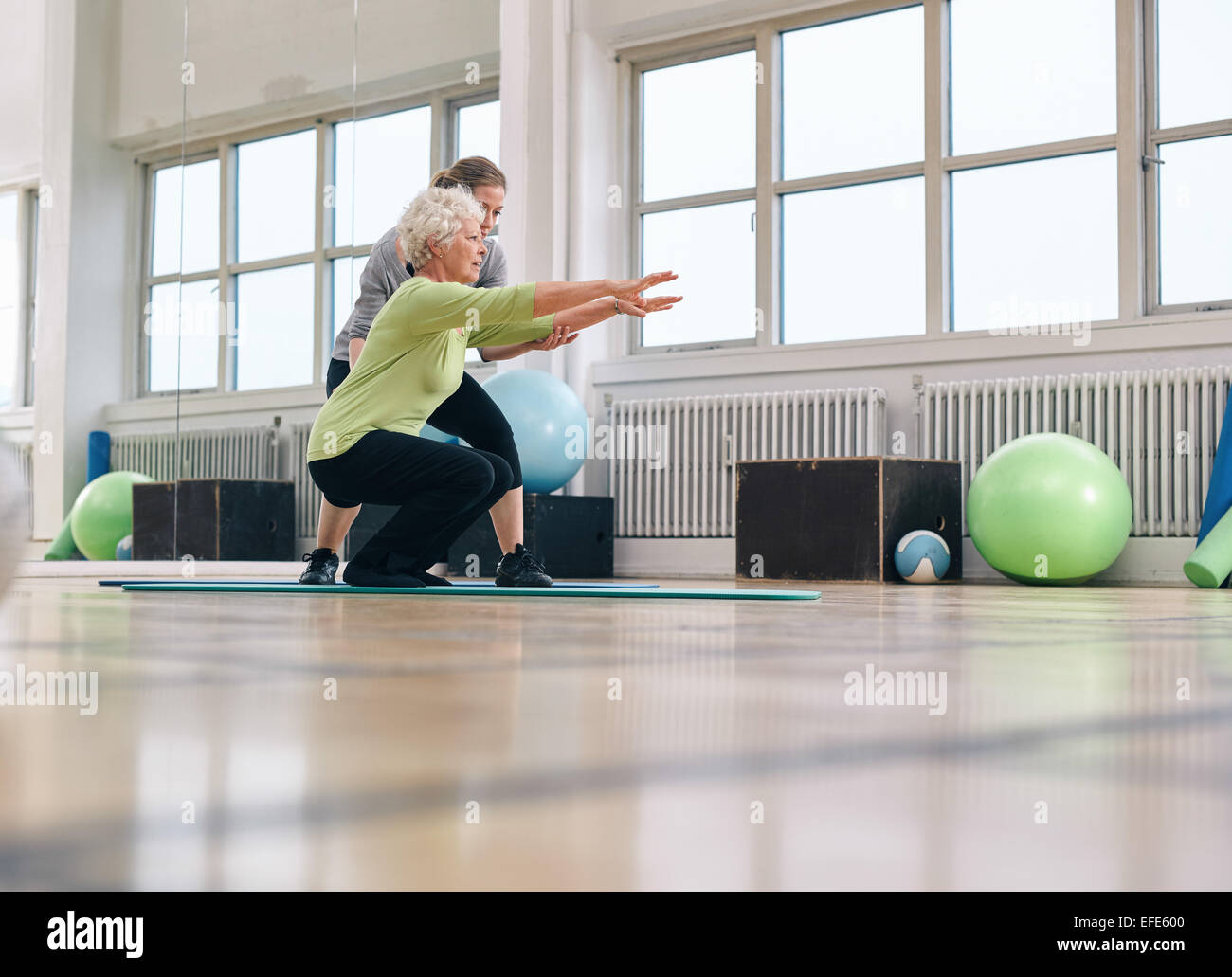 Senior woman doing exercise with her personal trainer at gym. Gym ...