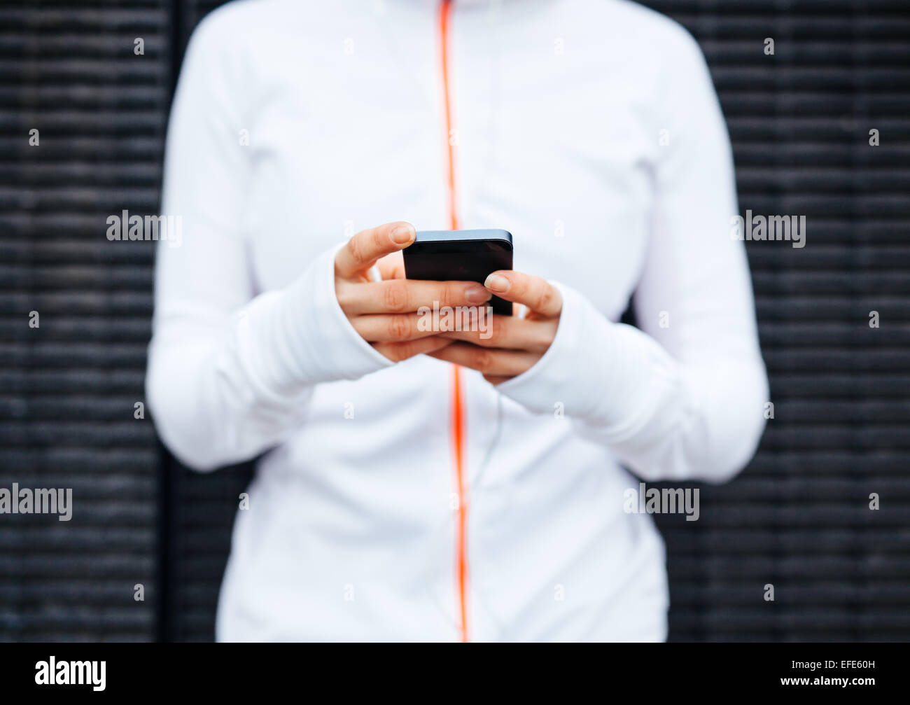 Closeup of young woman taking a break form workout using mobile phone. Focus on hands and smart phone. Stock Photo