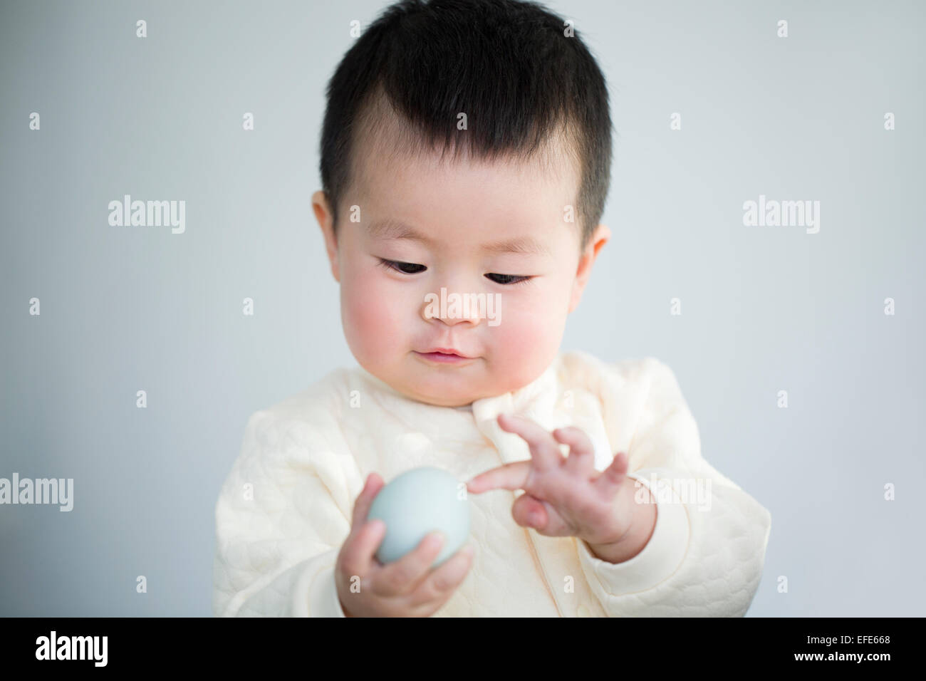 Cute baby holding duck egg Stock Photo