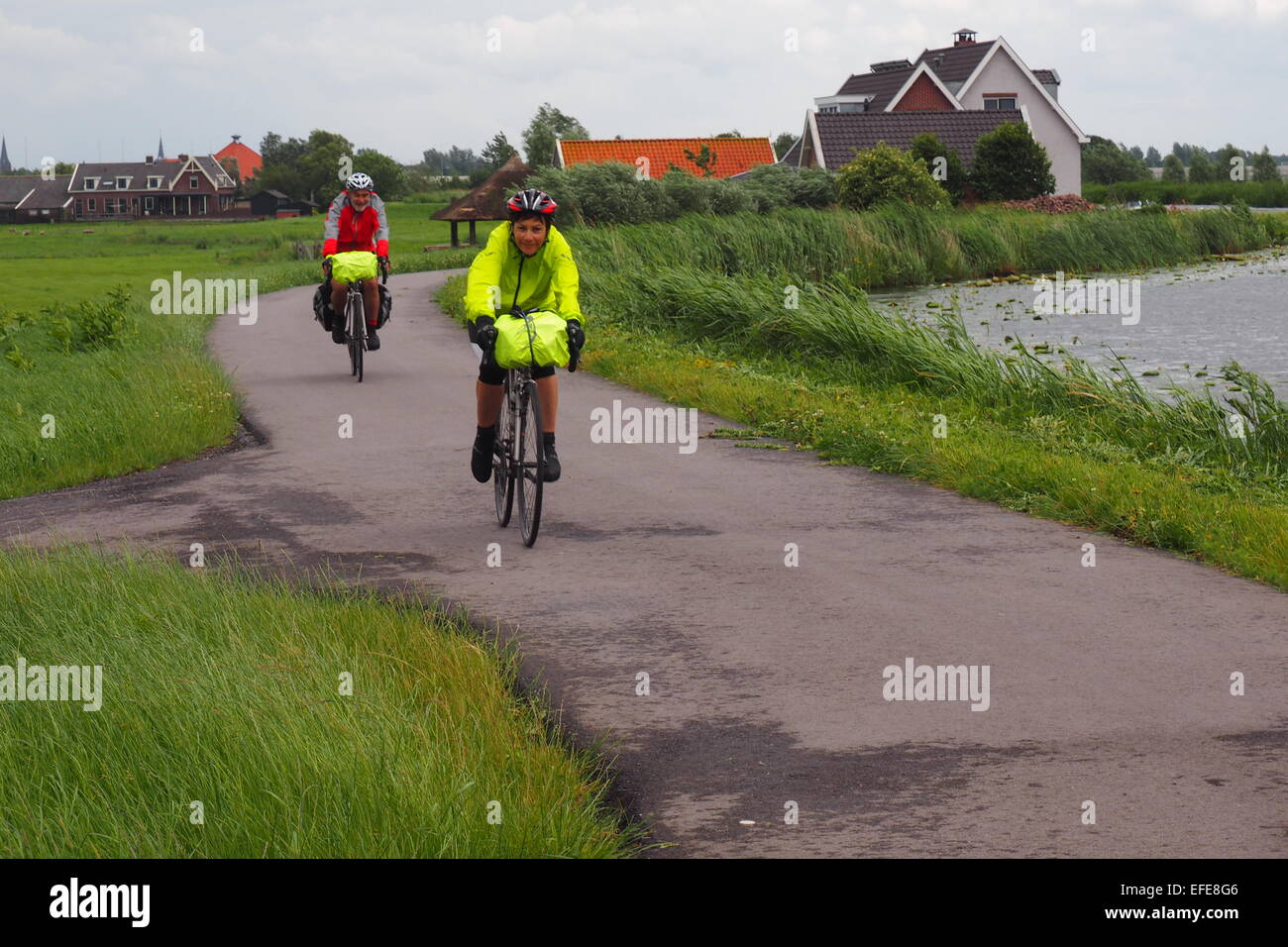 Two cyclists cycling on a bike path along the Amstel River on the outskirts of Amsterdam. Stock Photo