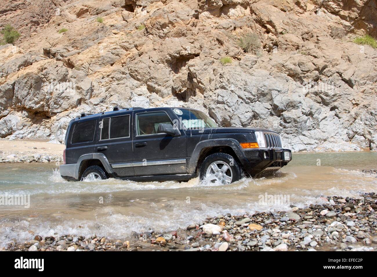 A Jeep Commander 4x4 vehicle negotiates a river in the desert interior of the Sultanate of Oman. Stock Photo